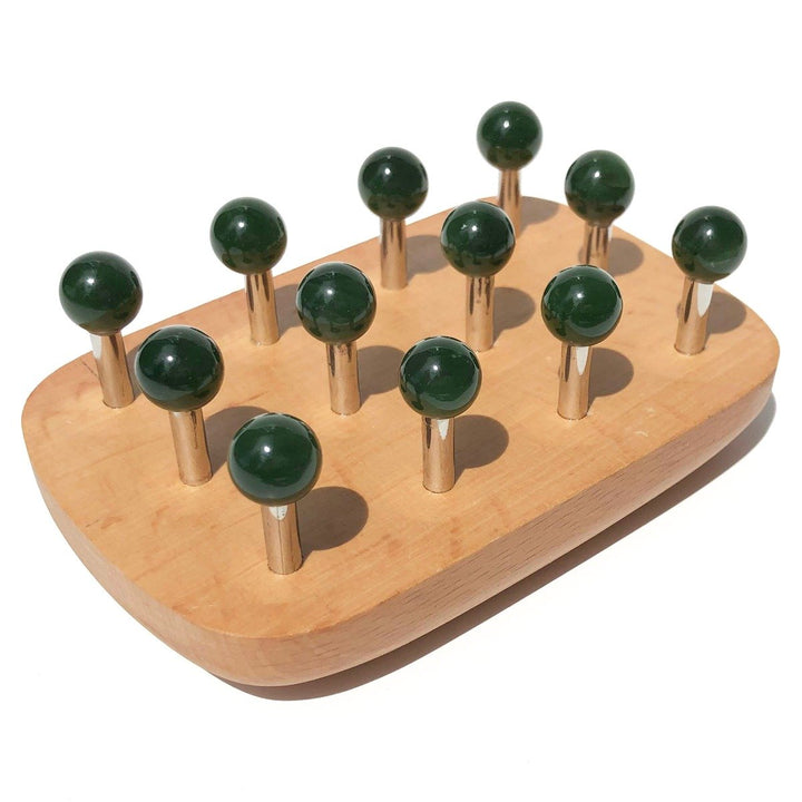 Angled view of wooden massage tool with dark green ball knobs on metal pegs