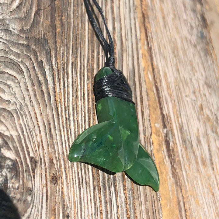 Green jade whale tail pendant wrapped in black cord