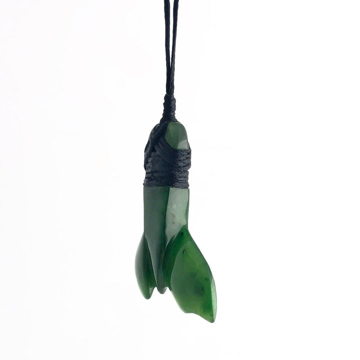 Green jade whale tail pendant wrapped with black cord against a white background.