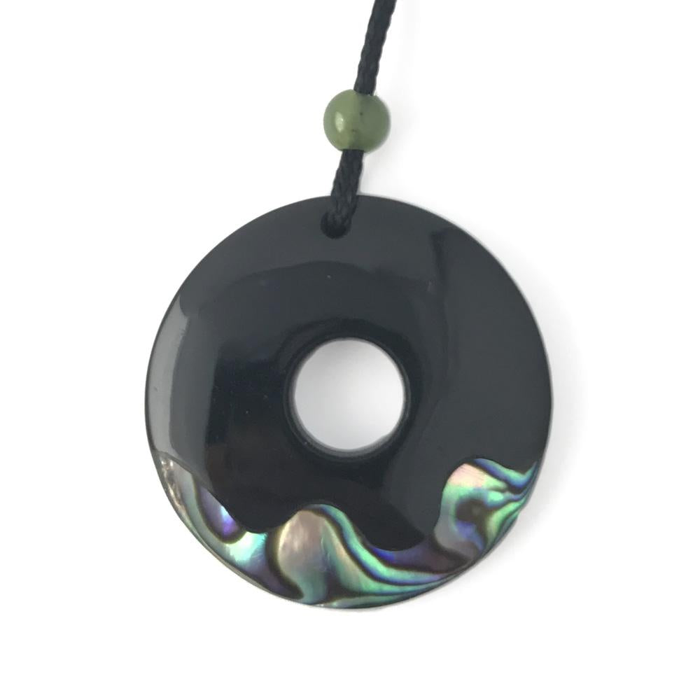 Black donut pendant with central hole and iridescent shell inlay along the lower rim.