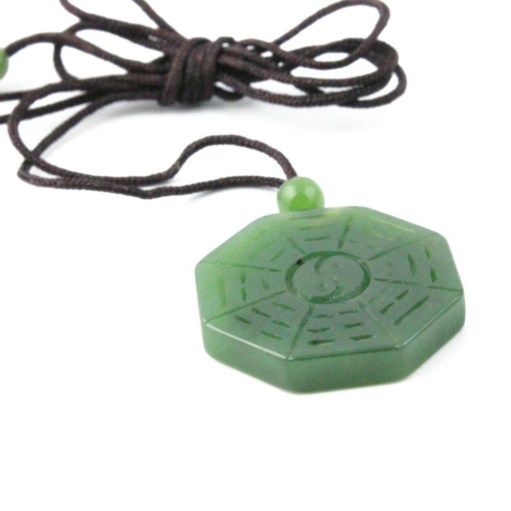 Close-up of a green octagonal pendant on a brown cord necklace with a small green bead