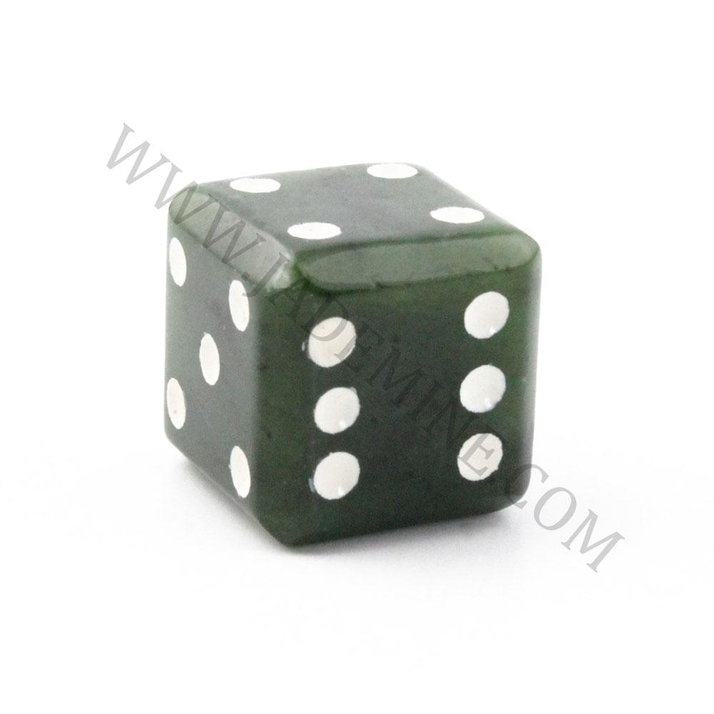 Close up of a single dark green jade die showing white pips