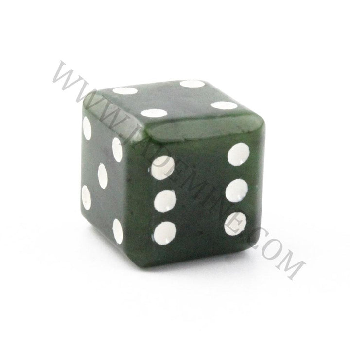 Close up of a single dark green jade die showing white pips