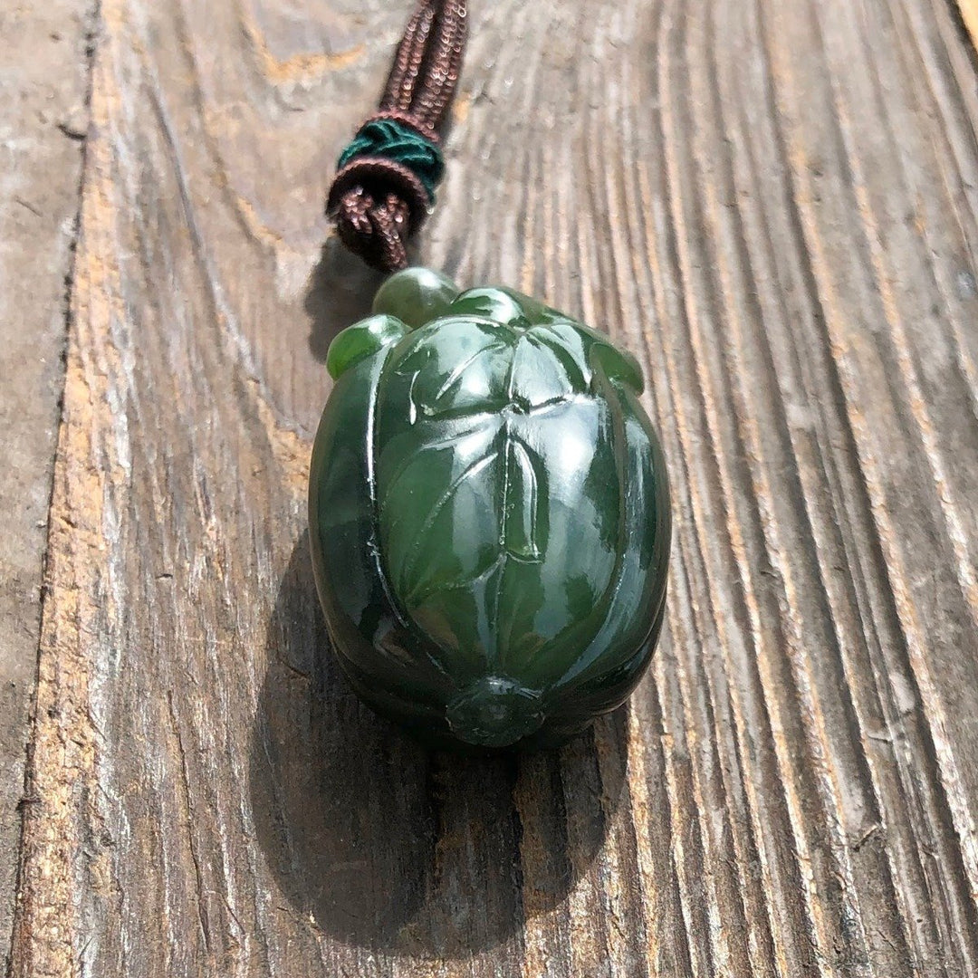 Close-up of green jade squash pendant showing detailed leaf carving.