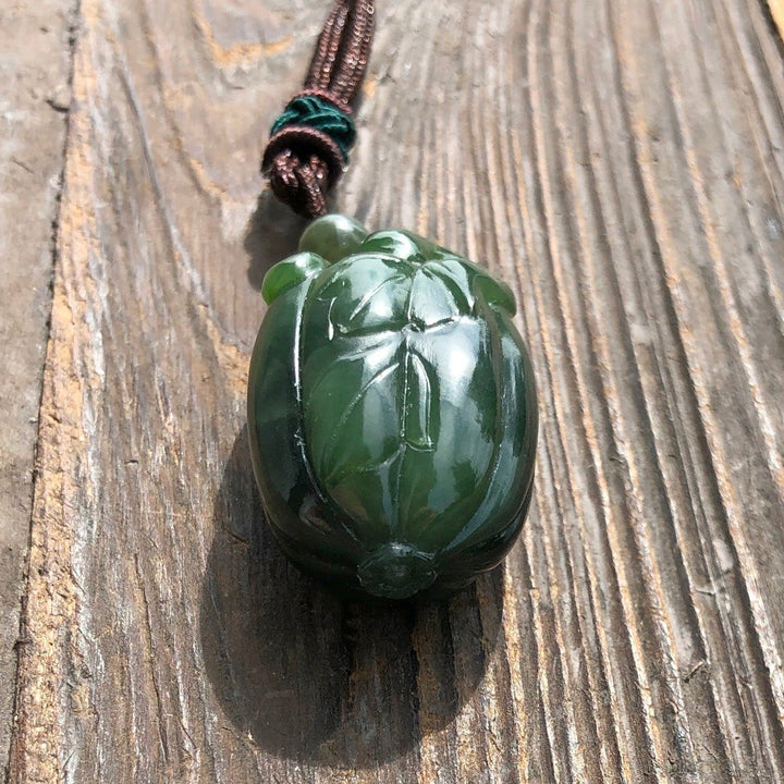 Close-up of green jade squash pendant showing detailed leaf carving.