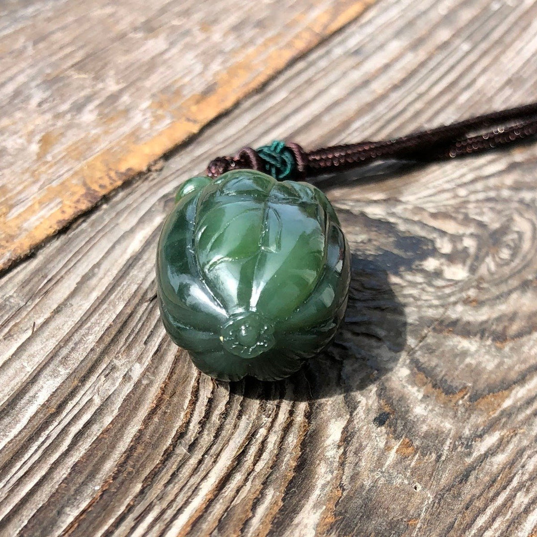 35mm green jade squash pendant on a brown cord laid on weathered wood.
