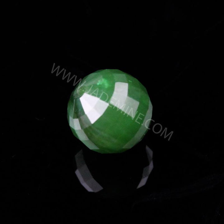 Single 12mm green faceted bead on a black surface