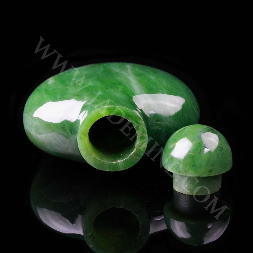 Green jade perfume bottle shown on its side with open neck and detached cap nearby.