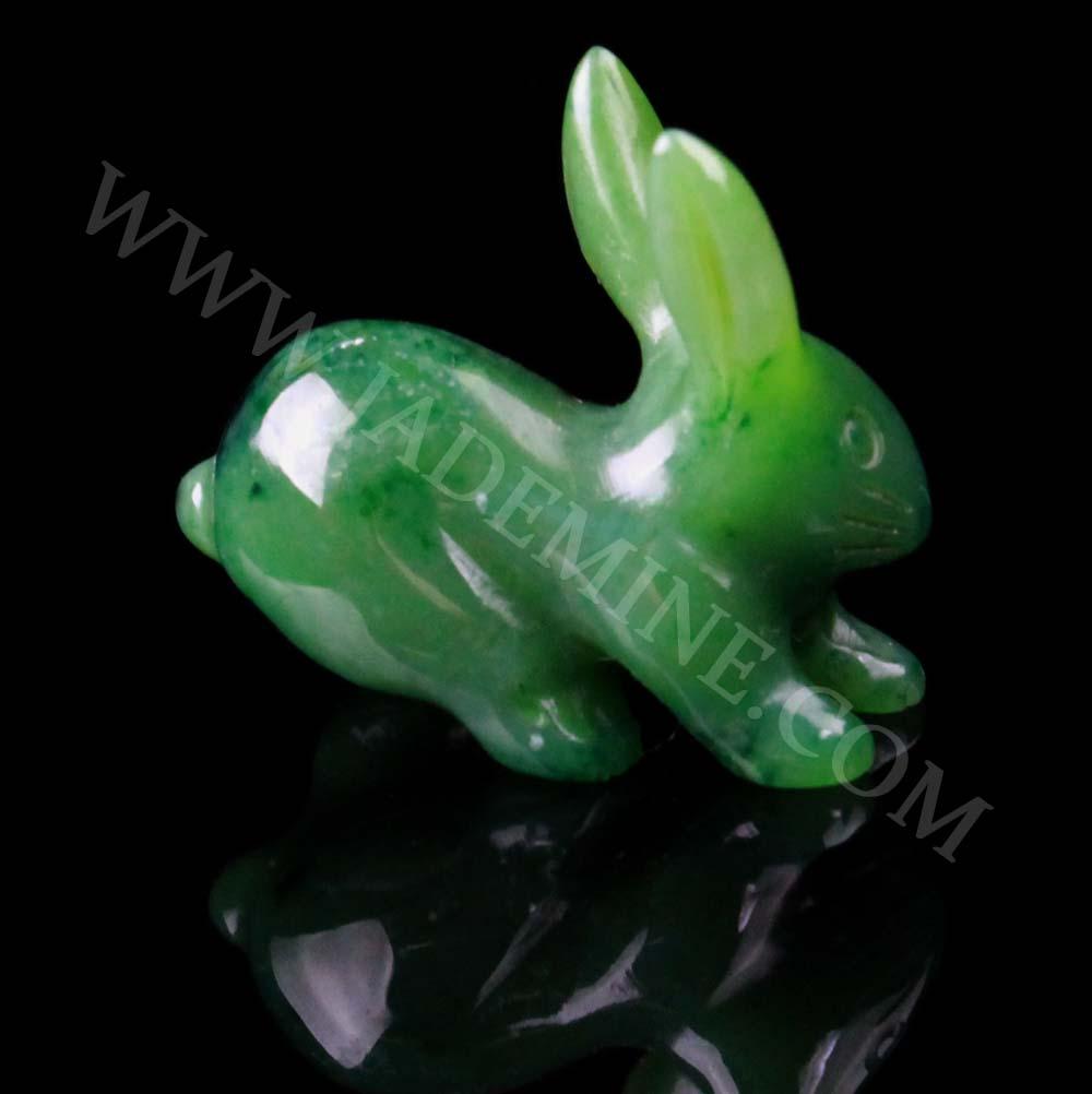 Green jade rabbit carving lying on its side against a black background