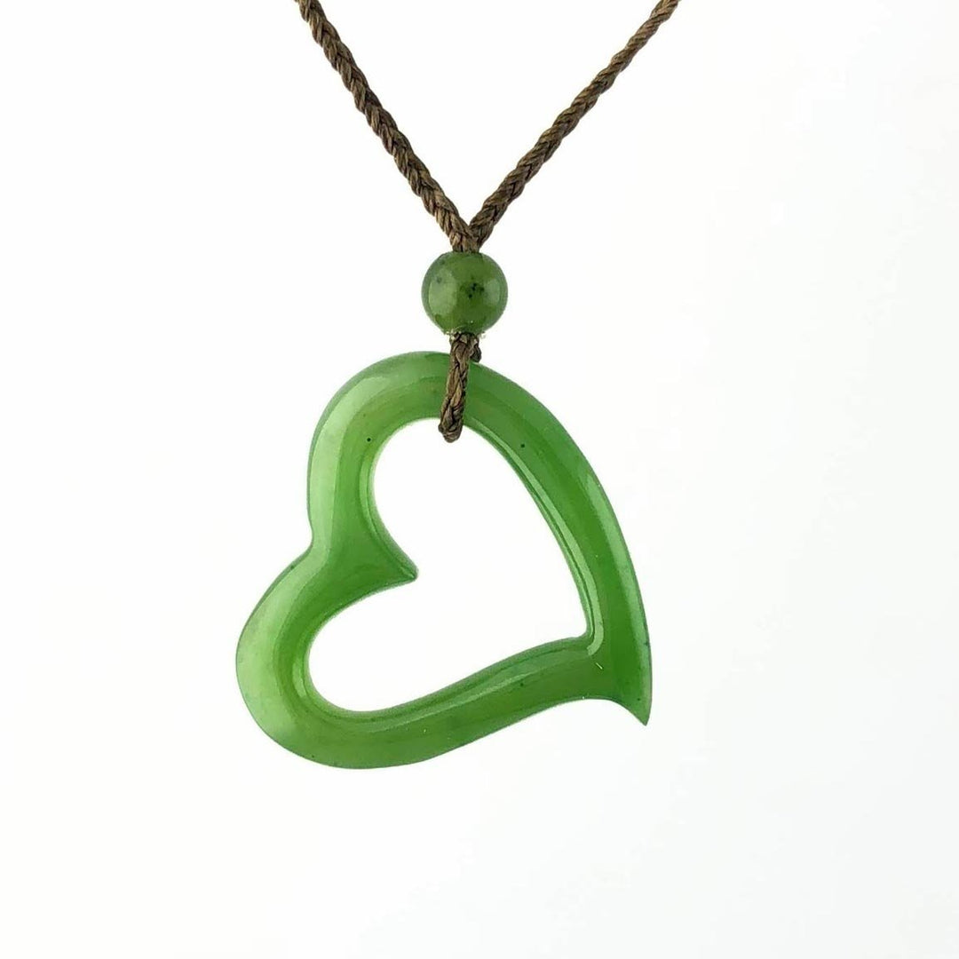 Green hollow heart pendant on a braided brown cord with bead against a white studio background