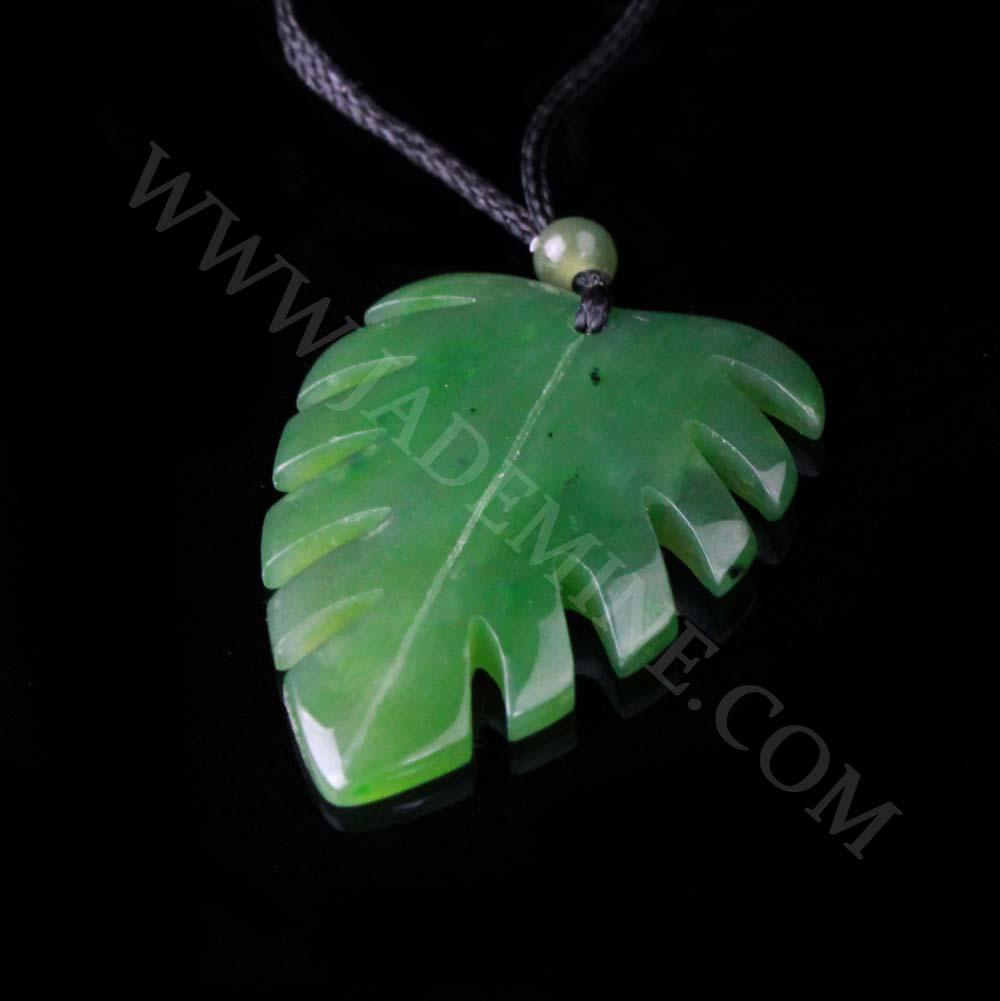 Jade Monstera leaf pendant on a black cord with a bead, photographed at a slight angle on black background.