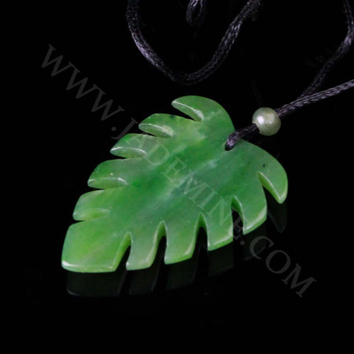 Jade Monstera leaf pendant on a black cord with a bead, displayed on a black background.