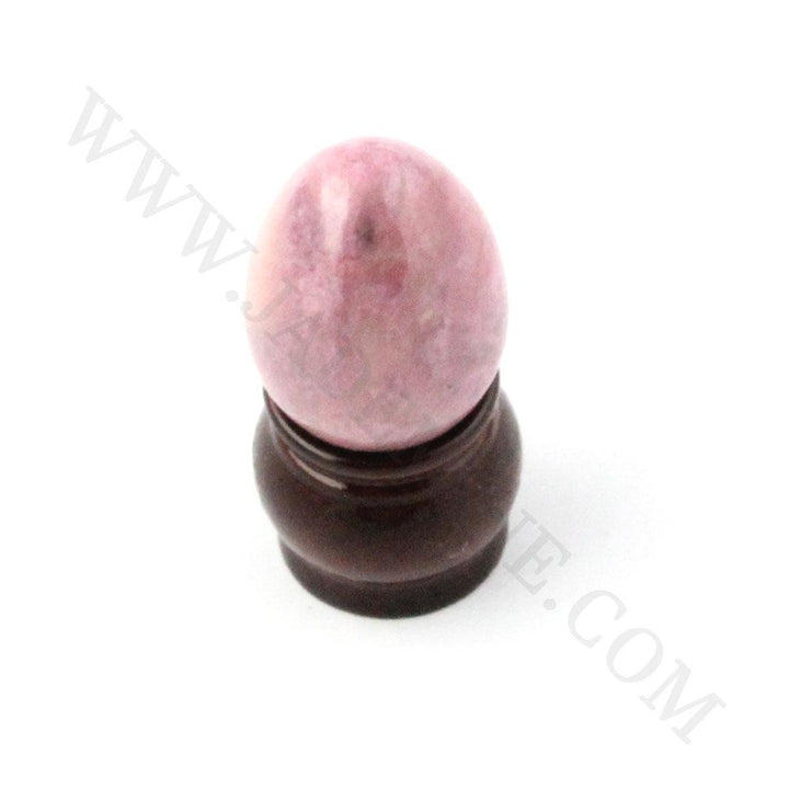 Pink rhodonite egg with natural veining on a white surface