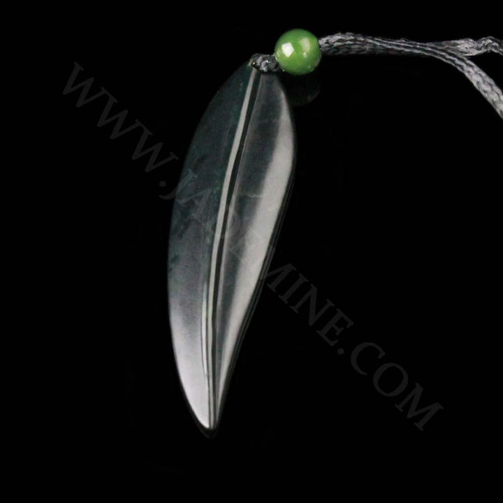 Leaf pendant on a black cord with a green bead, side view of the dark elongated leaf