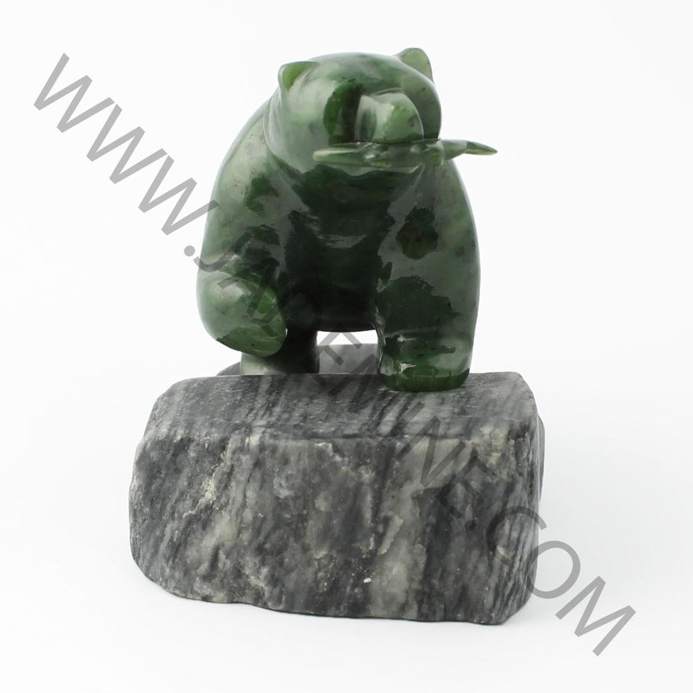Green bear statue perched on a dark granite base.
