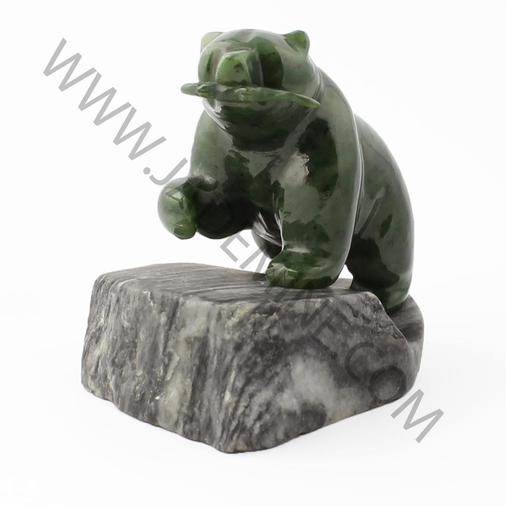 Green jade bear sculpture perched on a gray granite base