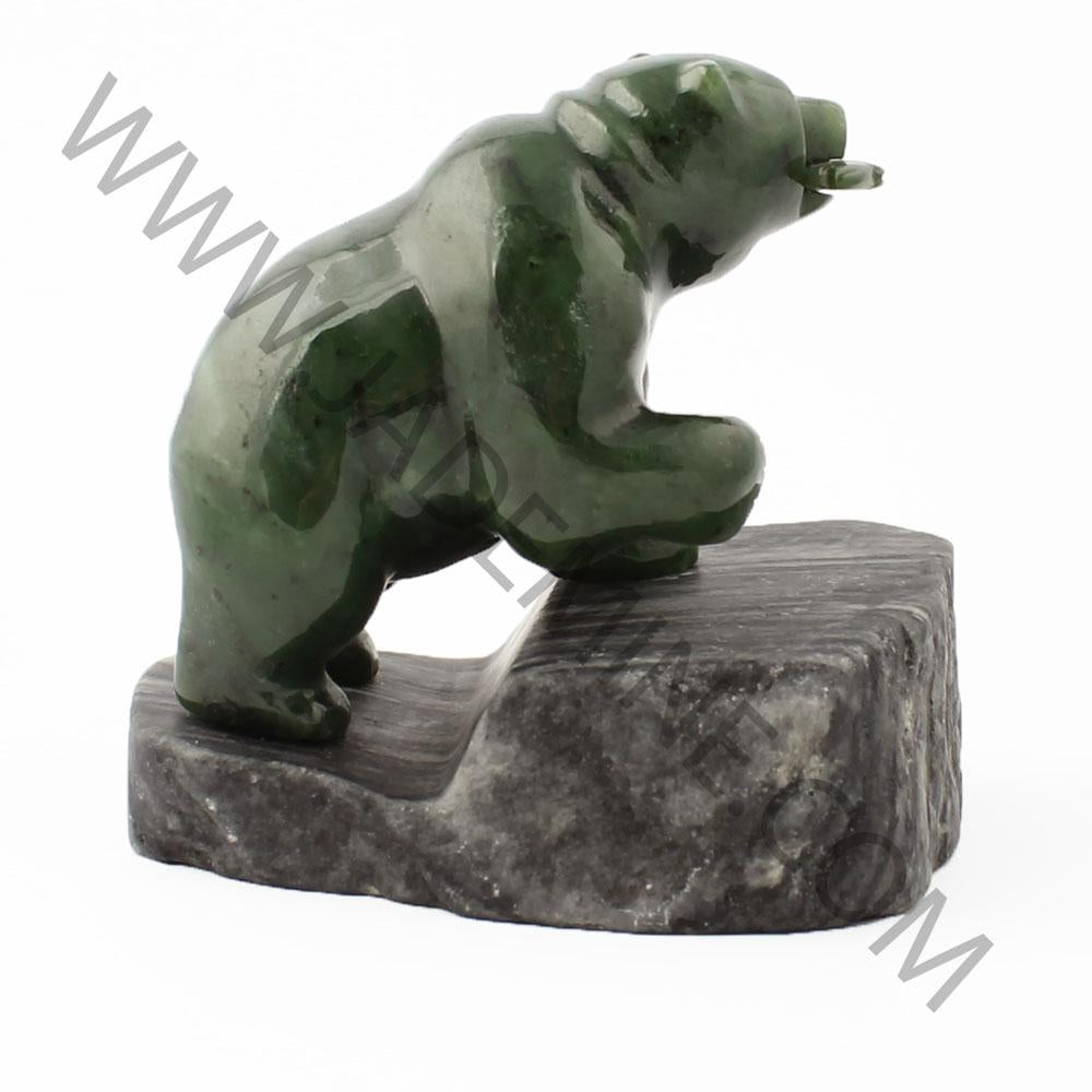 Side view of green bear statue on a dark granite base.