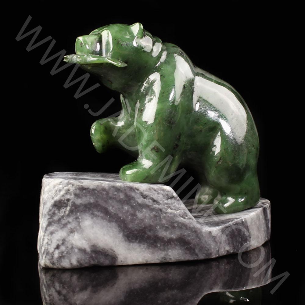 Green jade bear perched on a gray granite base