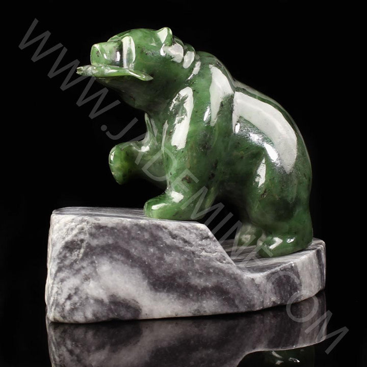 Green jade bear perched on a gray granite base