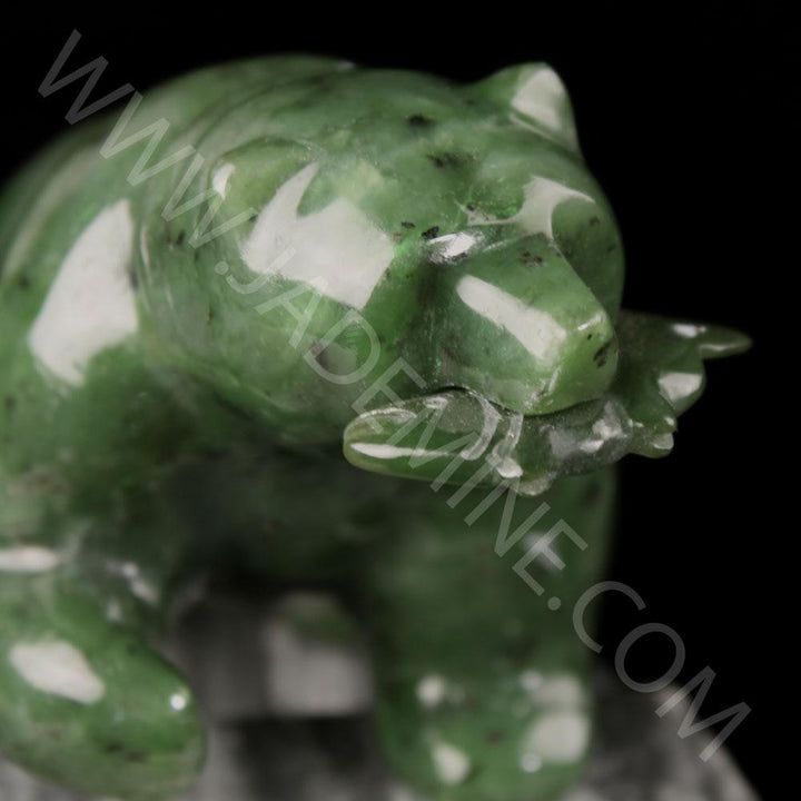 Close up of a green jade bear sculpture with white mottling against a black background