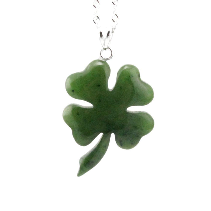 Green jade shamrock pendant hanging from a silver chain against a white background