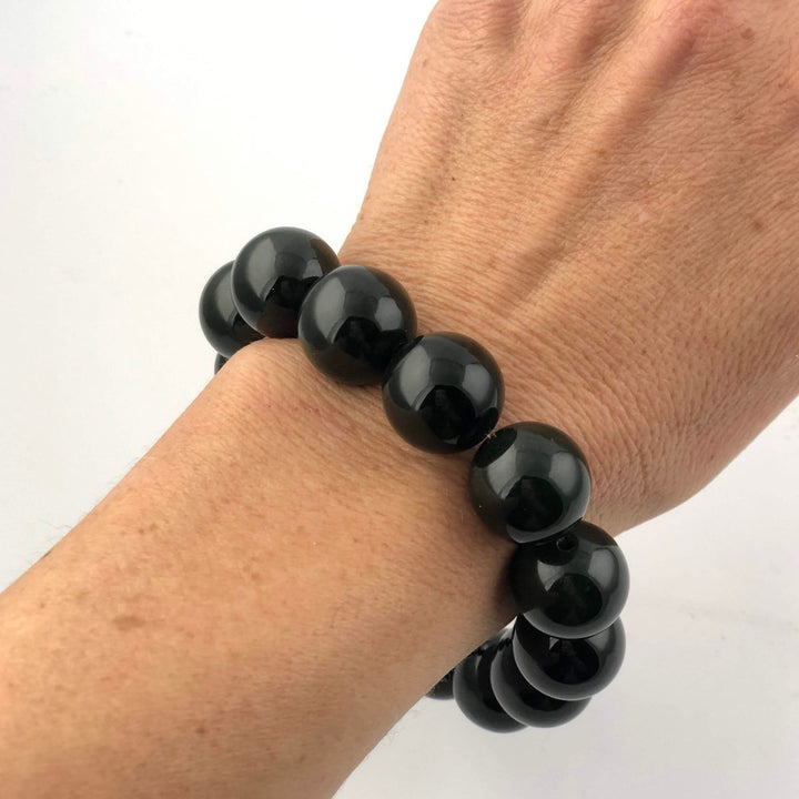 Bead bracelet with glossy black 16mm beads worn on the wrist.