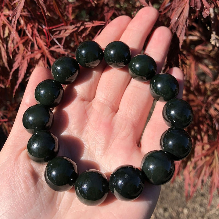 Bead bracelet with glossy dark green 16mm beads held in a palm.