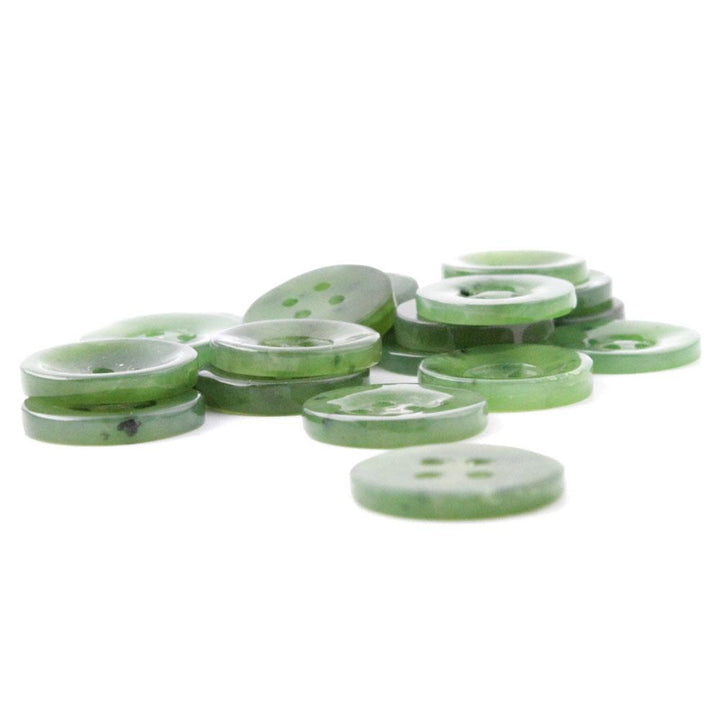 Pile of translucent green four hole buttons on white background