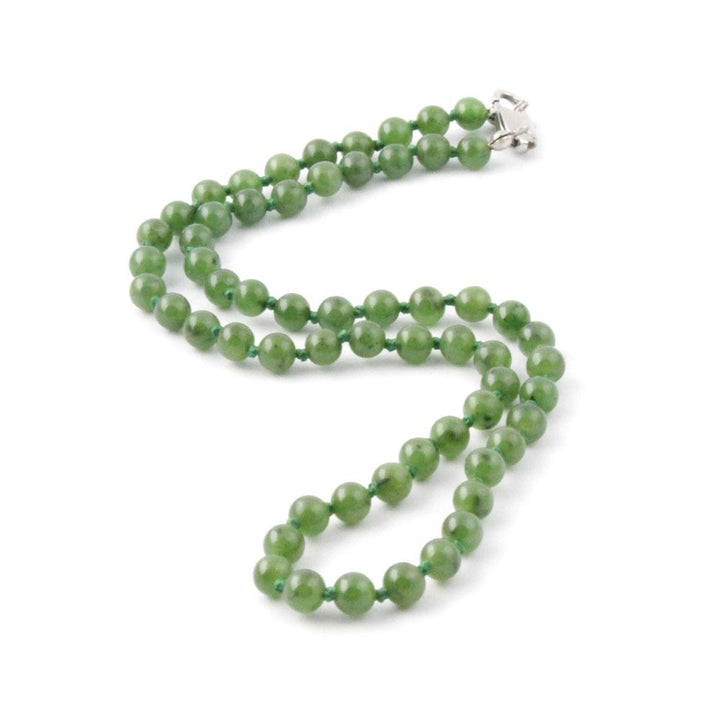 Green jade bead strand with a silver clasp on a white background.