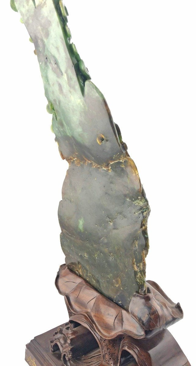 Close up of the jade dragon showing green stone with natural variations and carved base at bottom.