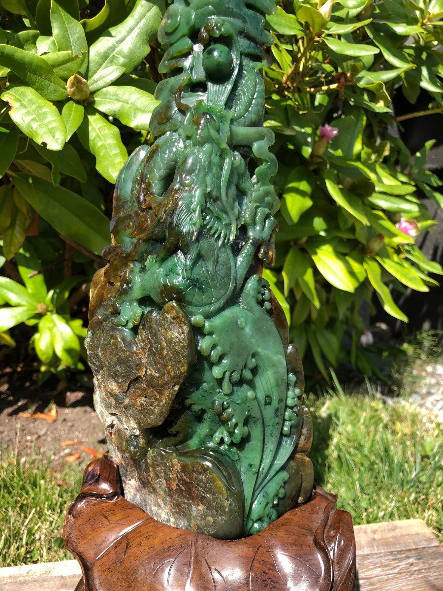 Jade Dragon statue carved from green jade with intricate dragon details perched on a rocky base with a wooden pedestal
