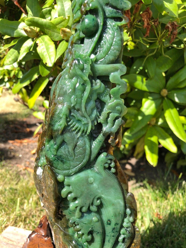 Side view of Jade Dragon Statue carved from green jade showing flowing scales and a rocky base