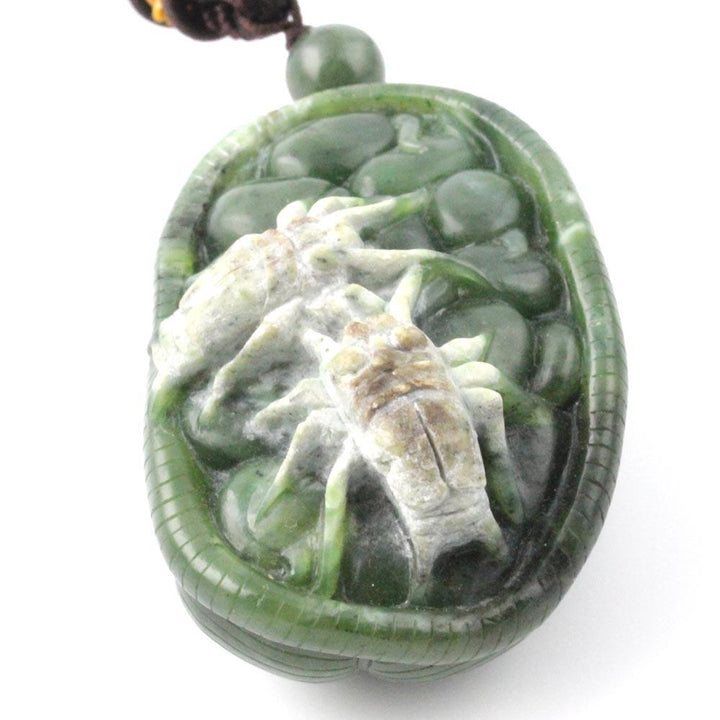 Green jade oval pendant with a pale white spider carving inside on a brown cord.