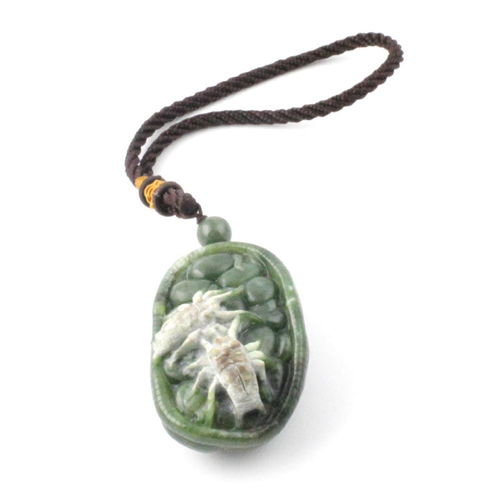 Green jade oval pendant with pale white spider carving, hanging from a braided brown cord.