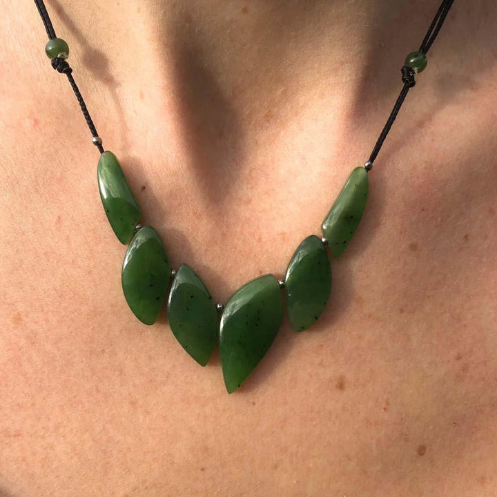 Green jade leaf bead necklace draped on a person with a black cord