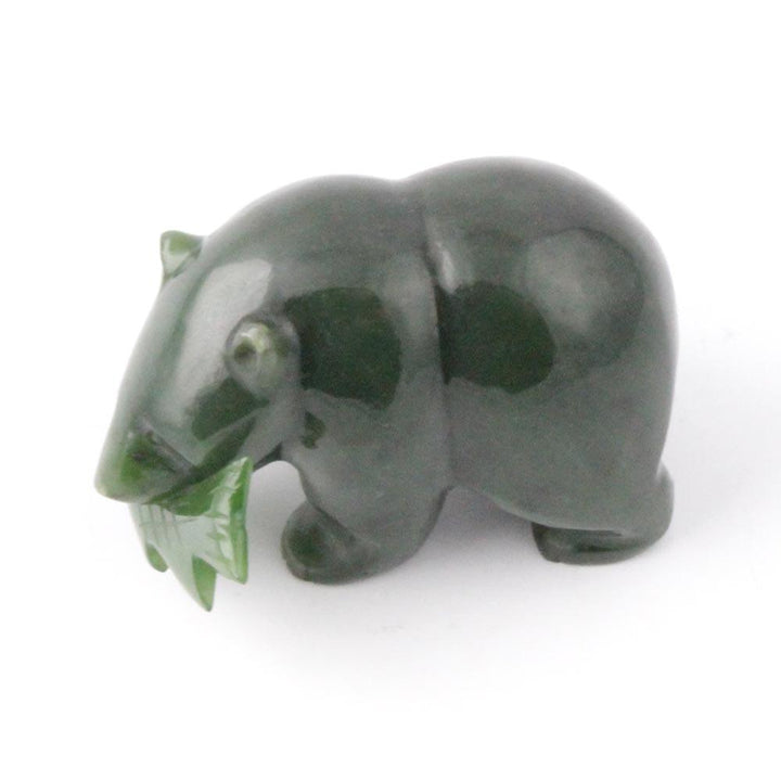 Side view of a dark green grizzly bear figurine with a fish in its mouth