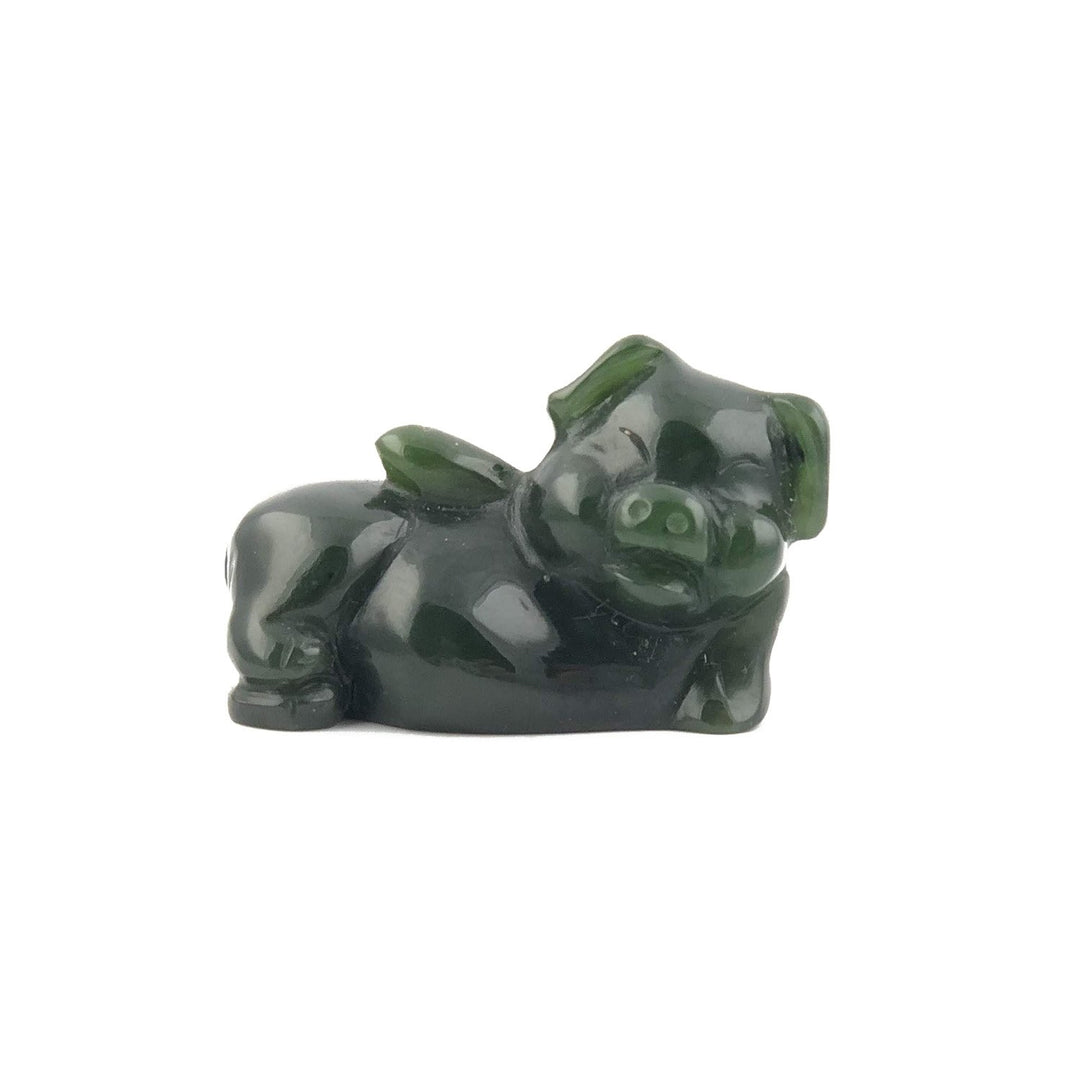 Dark green glossy pig figurine lounging on its side with its snout visible