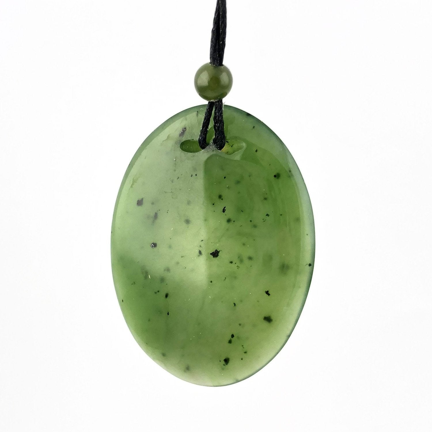 Oval green jade pendant on a black cord with a small green bead above