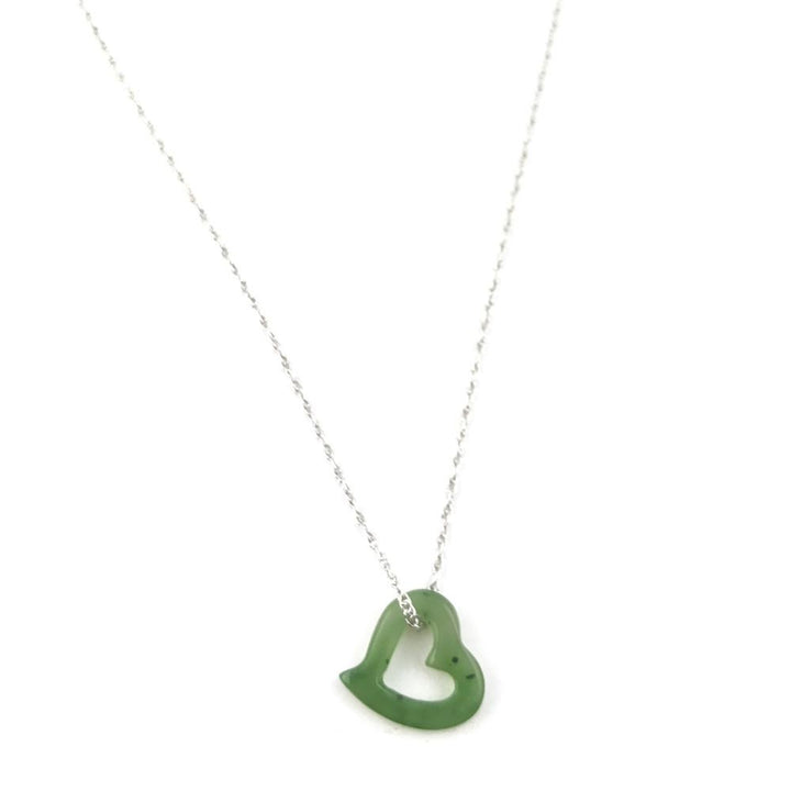 Green jade heart pendant with a hollow center on a silver chain against a white background