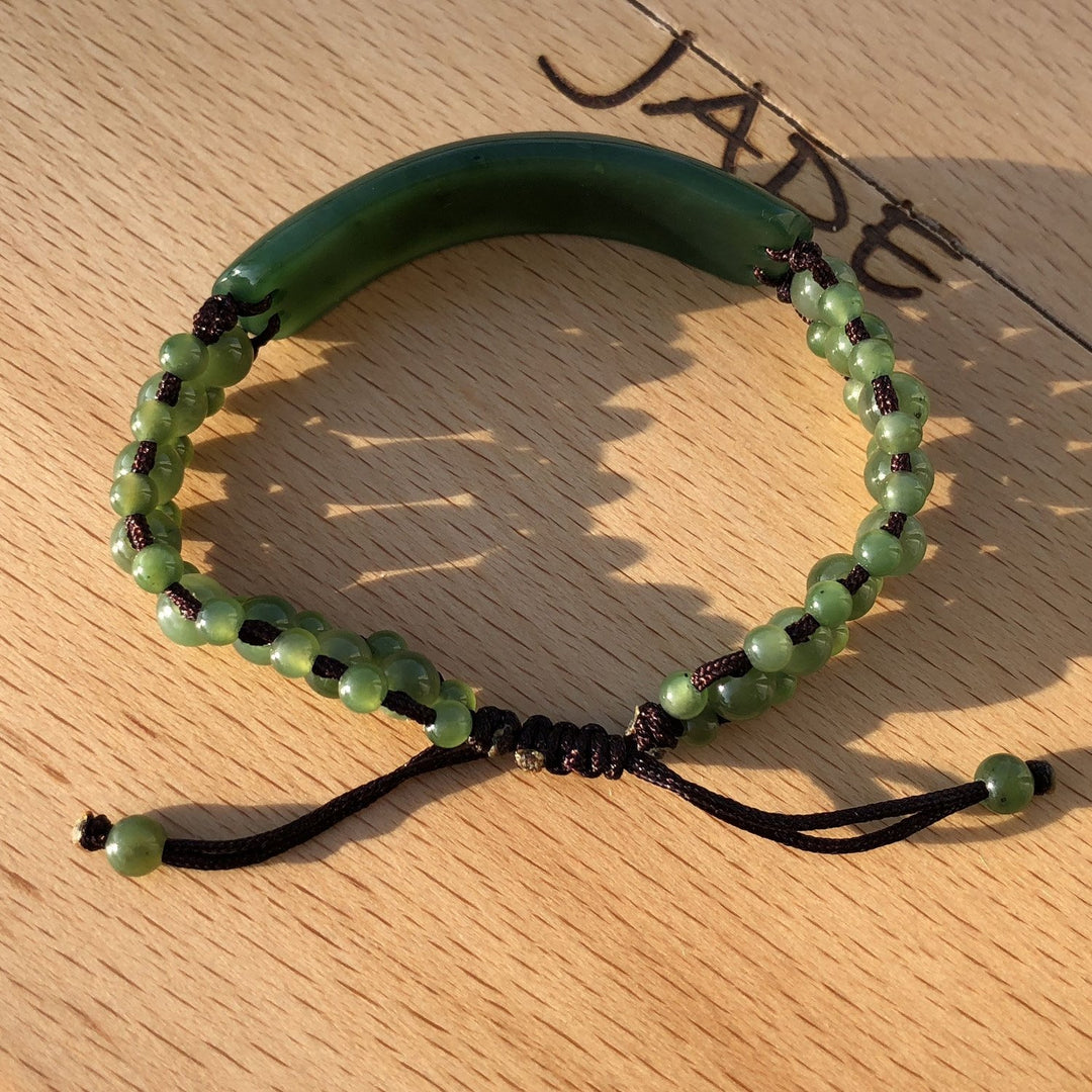 Close-up of green jade bead bracelet showing multiple green beads threaded on dark cord with knotted closures