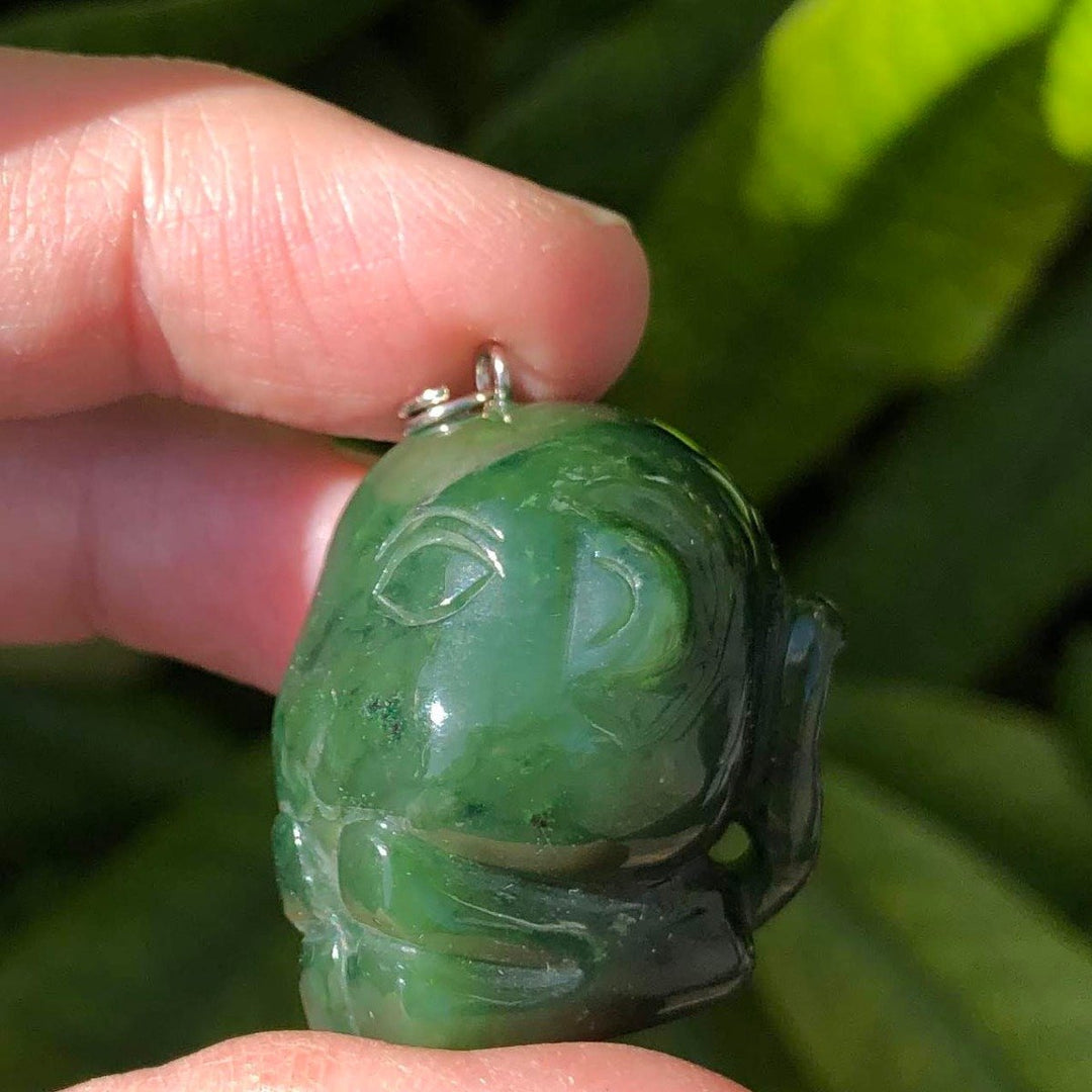 Hand held green jade cartoon monkey charm with carved face and loop at top.