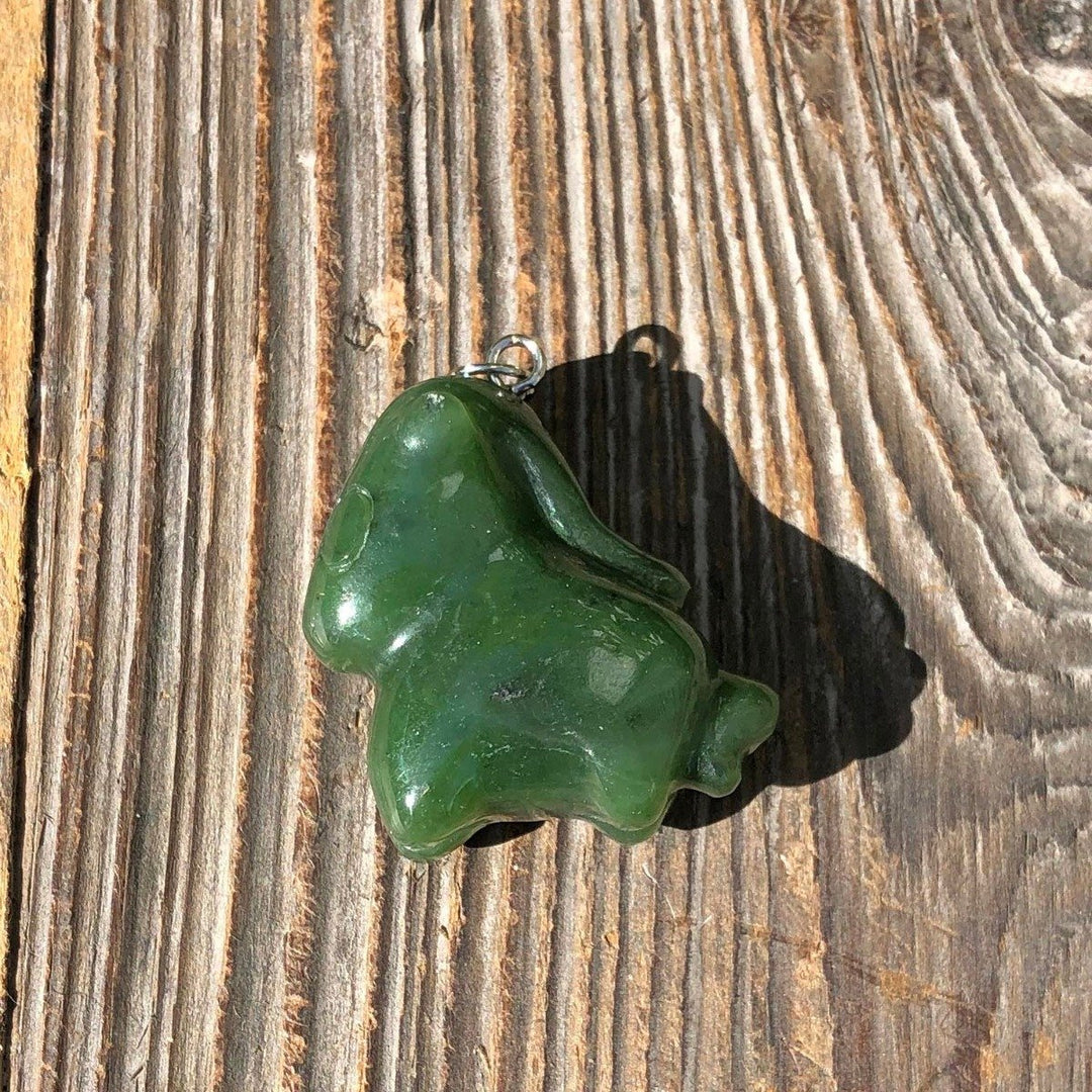 Green cartoon horse pendant shown on a rustic wooden surface.