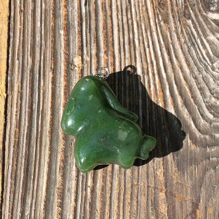 Green cartoon horse pendant shown on a rustic wooden surface.