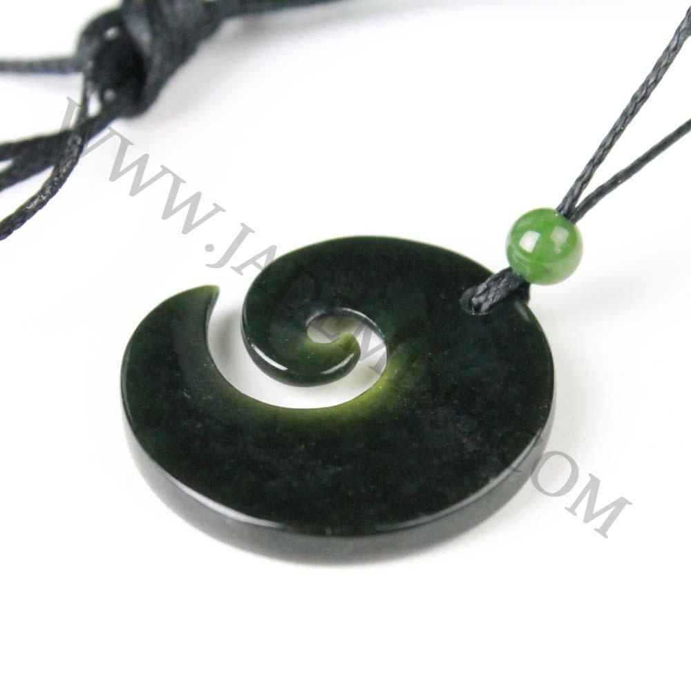 Dark green jade donut pendant with spiral inner cut on a black cord, accented by a small green bead