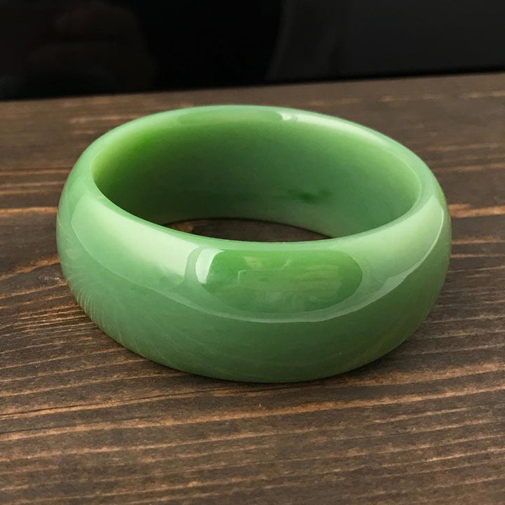 Green jade bangle resting on a wooden surface
