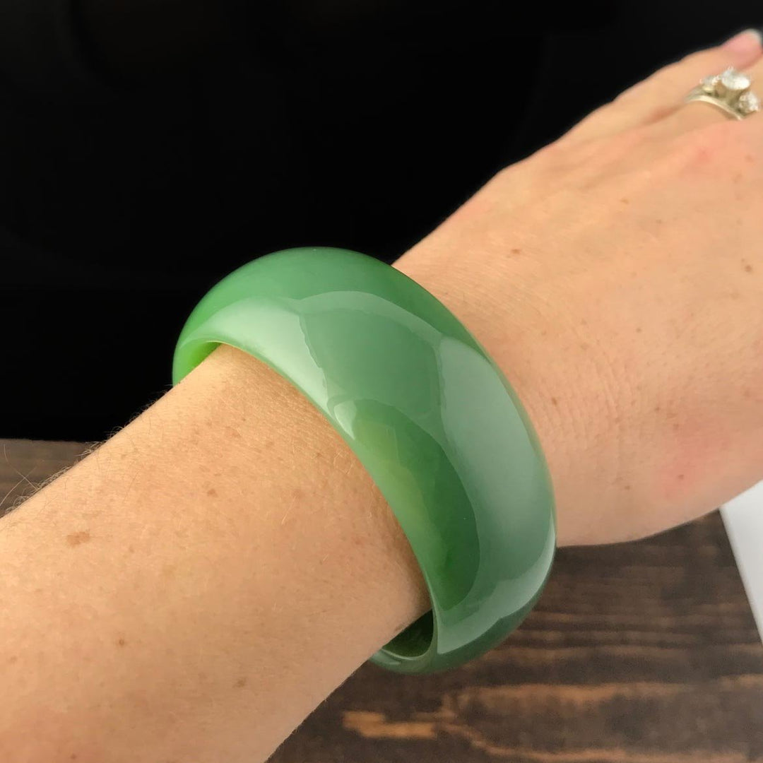 Wrist shot showing a glossy green jade bangle worn on the wrist