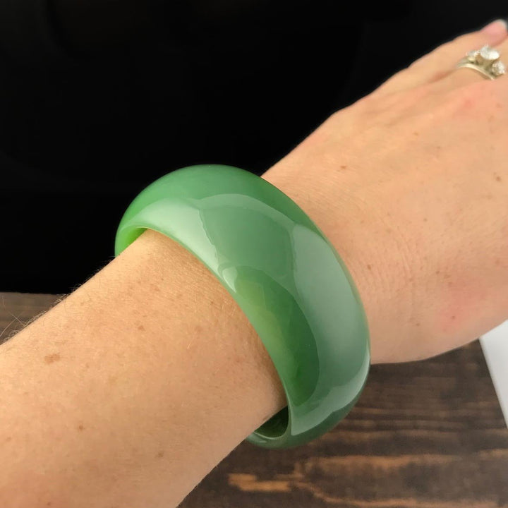 Wrist shot showing a glossy green jade bangle worn on the wrist