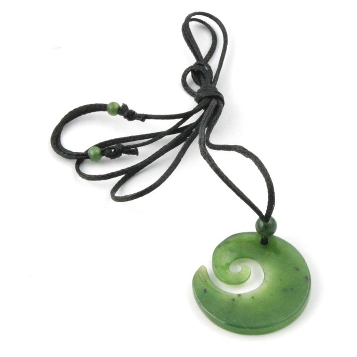 Green jade Spiral on a a black wax cord, with a white backround