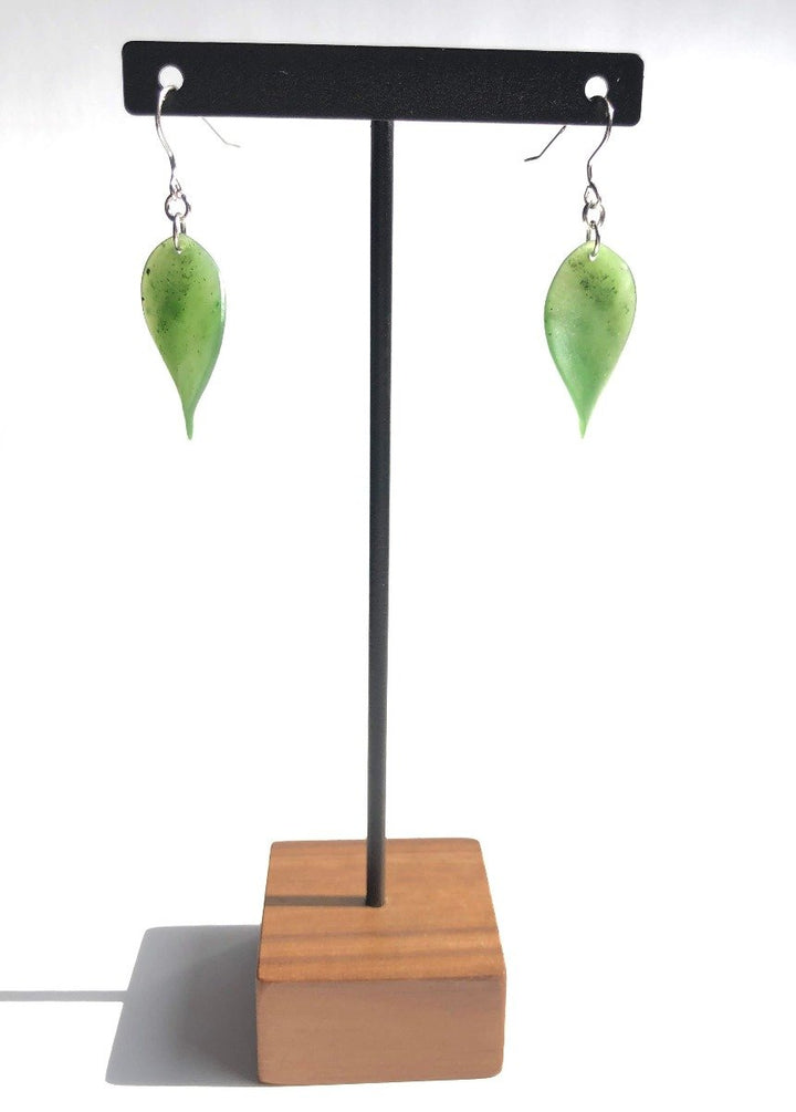 Leaf 1884 green leaf earrings displayed on a stand with a wooden base