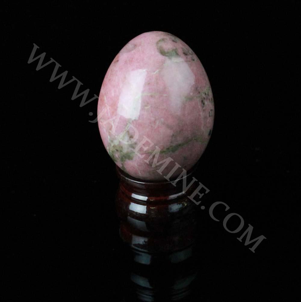 Pink rhodonite egg on a dark wooden stand